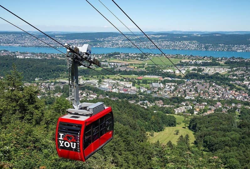 Gondel der Felseneggbahn über dem Wald, darunter Adliswil, im Hintergrund der Zürichsee